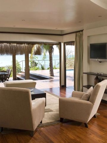 Eleganter Wohnbereich mit Meerblick und Zugang zur Terrasse mit Palmen.