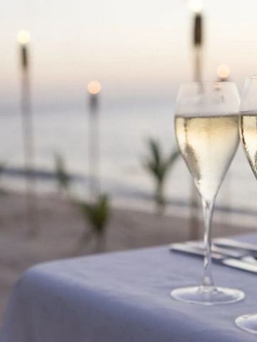 Romantischer Sonnenuntergang mit Sektgläsern am Strand