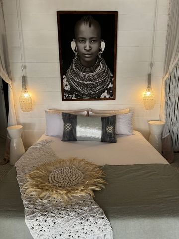 Elegantes Schlafzimmer mit afrikanischem Kunstwerk und warmem Licht.