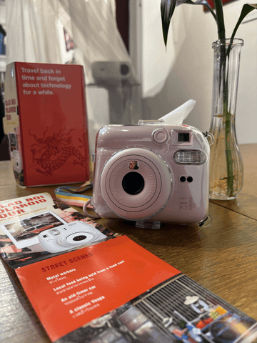 Eine Polaroid-Kamera liegt neben einer aufgeschlagenen Stadtkarte – bereit für die nächste spannende Fototour durch die lebendigen Straßen der Stadt.