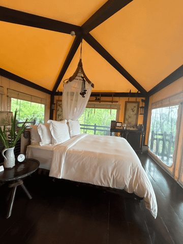Luxuriöses Schlafzimmer mit großem Himmelbett und hellen Textilien in einem Zelt.