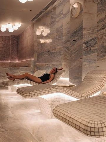 Wellnessbereich mit bequemen Liegen aus Marmor und warmer Beleuchtung.