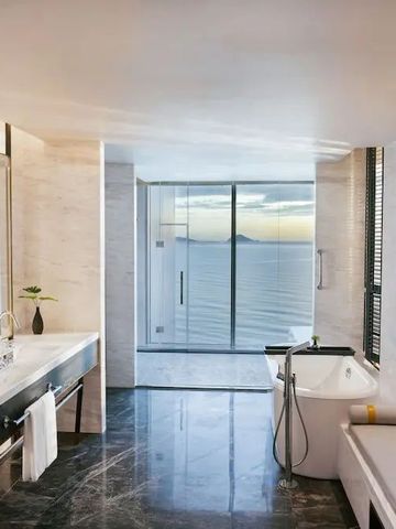 Großzügiges Badezimmer mit freistehender Badewanne und Fenstern mit Meeresblick.