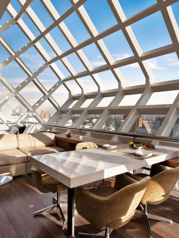 Modern eingerichteter Sitzbereich mit großem Glasdach und Blick auf die Stadt.