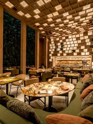 Stilvoller Restaurantbereich mit beleuchteter Holzdecke und Tischen.