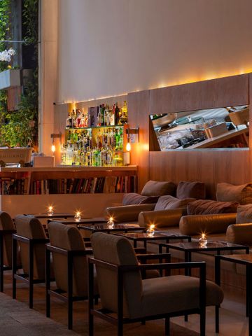 Loungebereich der Bar mit einer langen Sitzreihe, Holzverkleidung und Beleuchtung.