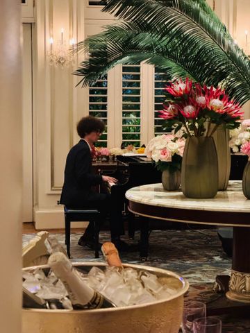 Pianist in einem luxuriösen Raum bei floraler Dekoration und gekühltem Champagner
