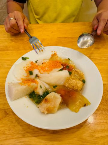 Vietnamesische Speisen auf Teller mit Essstäbchen und Löffel auf Holztisch