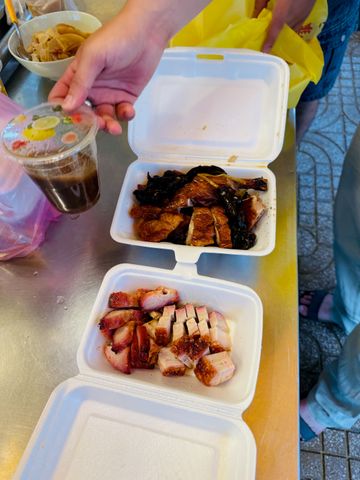 Asiatische Gerichte in Styropor-Boxen mit Getränk auf einem Tisch serviert