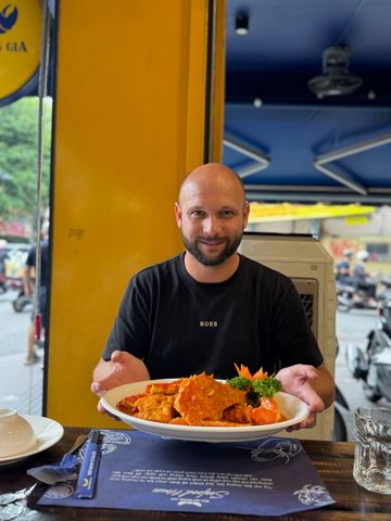 Mann zeigt ein Gericht mit Krabben in roter Sauce in einem Restaurant