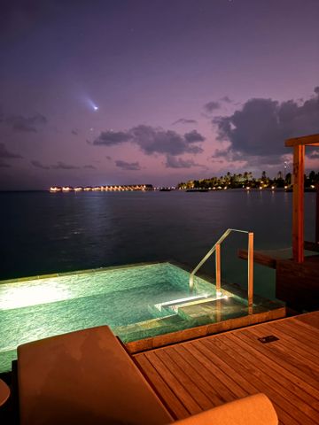 Infinity-Pool bei Dämmerung mit Blick auf das beleuchtete Meer und den abendlichen Himmel.