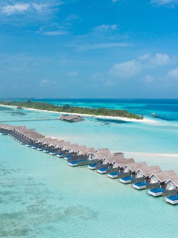 Reihe von luxuriösen Überwasser-Villen im klaren türkisen Meer mit blauem Himmel