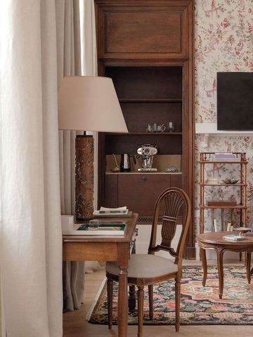 Sitzbereich im Zimmer mit Holzschreibtisch, Fernseher und gemustertem Teppich.