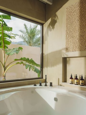 Luxuriöses Badezimmer mit runder Badewanne, großen Fenstern und Pflanzen