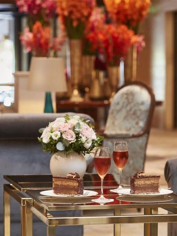 Elegante Lobby mit Blumenarrangement, Kaffee und Kuchen auf einem Tisch.