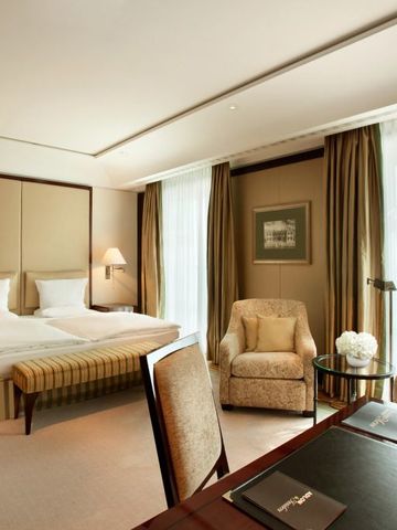Luxuriöses Zimmer mit großen Fenstern, Doppelbett und Schreibtisch.