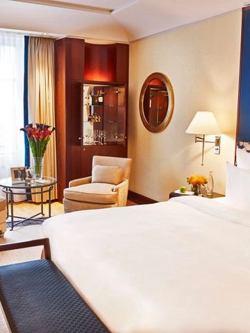 Geräumiges Zimmer mit Kingsize-Bett, Sesseln und eleganter Wandgestaltung.