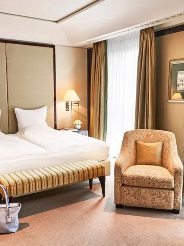 Elegantes Zimmer mit Doppelbett, Sessel und stilvollem Dekor.