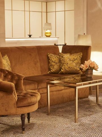 Luxuriöse Lounge mit goldenen Möbeln und Blumenarrangement im Hotel Adlon Kempinski Berlin.
