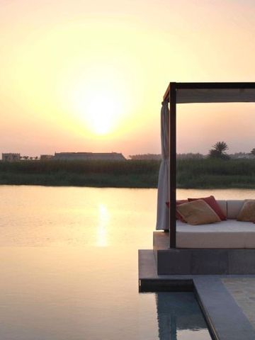 Sonnenuntergang über einem Infinity-Pool mit Tagesbett