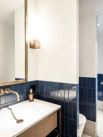 Helles Badezimmer mit blauen Fliesen und goldenen Armaturen