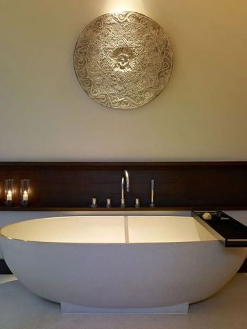 Luxuriöse Badewanne mit kunstvoller Wandverzierung im Hintergrund.
