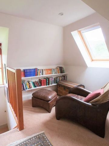Gemütlicher Lesebereich mit Sessel und Bücherregal unter einem Dachfenster