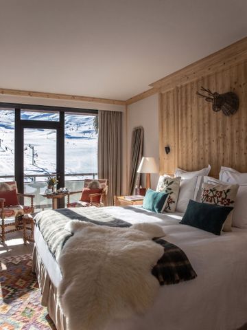 Komfortables Zimmer mit großem Fenster und atemberaubendem Alpenblick, rustikal dekoriert.