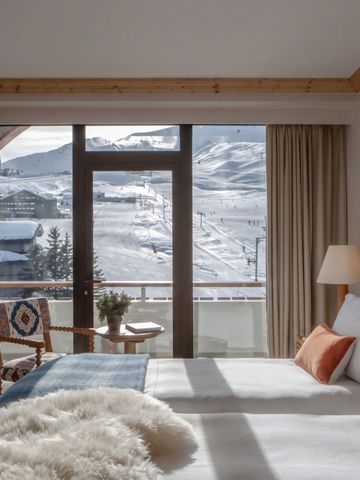 Hotelzimmer mit großen Fenstern und Blick auf verschneite Berge