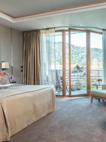 Geräumiges Zimmer mit großem Bett und Bergblick durch Glasfront