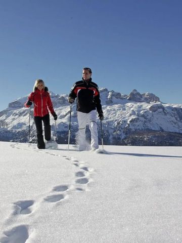 Menschen beim Schneeschuhwandern mit Berglandschaft im Hintergrund