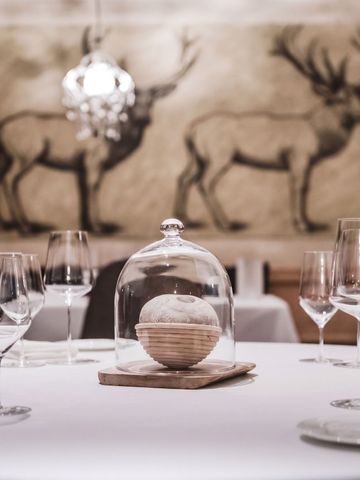 Gedeckter Tisch in einem Restaurant mit kunstvollen Hirschmalereien an der Wand