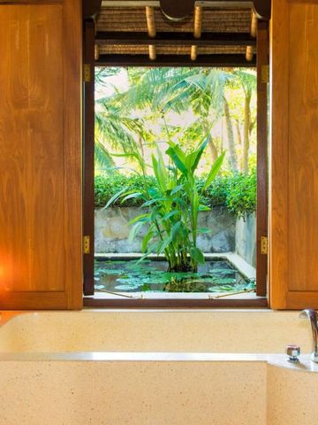 Badezimmer mit großer Badewanne und Blick auf einen privaten Garten