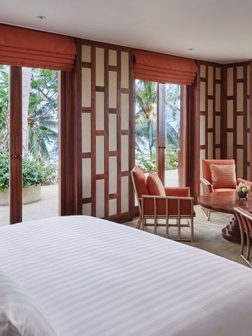 Geräumiges Zimmer mit Blick auf tropische Gärten und das Meer durch große Fenster