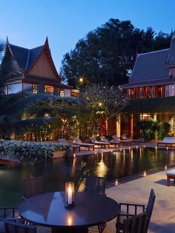 Luxuriöser Hotelpool bei Dämmerung mit eleganten Liegen und stilvollen Gebäuden.