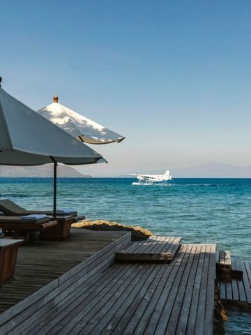 Seeterrasse mit Liegen und Sonnenschirmen über dem azurblauen Wasser