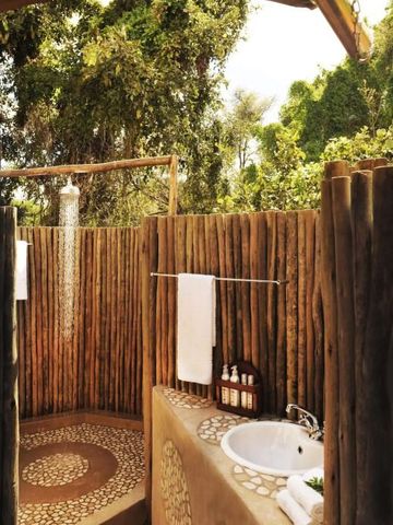 Freiluft-Dusche mit hölzernem Sichtschutz in natürlicher Umgebung