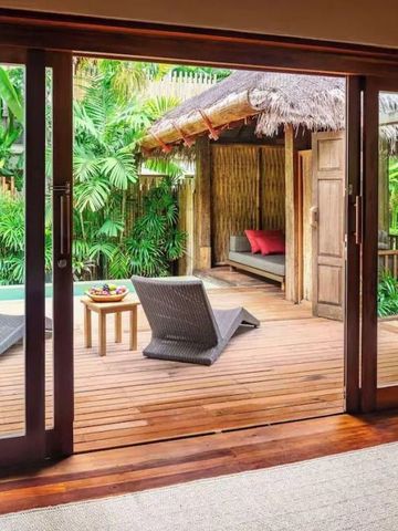 Private Terrasse mit Liegestühlen und tropischen Pflanzen.
