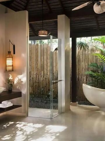 Offenes Badezimmer mit freistehender Badewanne und Blick auf tropische Pflanzen