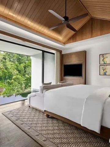 Geräumiges Schlafzimmer mit Holzdecke und Blick auf üppige grüne Umgebung