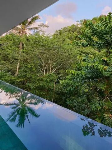 Infinity Pool mit Blick auf üppigen Dschungel und bewölkten Himmel