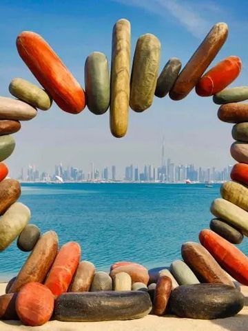 Steinskulptur am Strand mit Blick auf die Dubai Skyline über das Meer