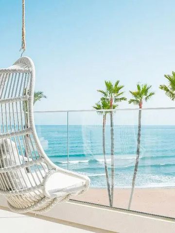 Balkon mit Hängesessel und Meerblick auf die Palmen und den Strand
