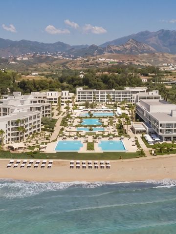 Gesamtansicht des Luxushotels am Strand mit Poolanlagen und Bergen im Hintergrund