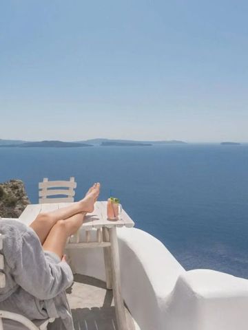 Frau entspannt auf Terrasse mit Meerblick und Cocktail