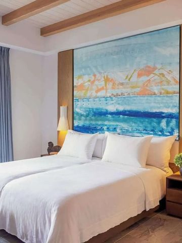 Komfortables Hotelzimmer mit großem Kunstwerk über dem Bett.