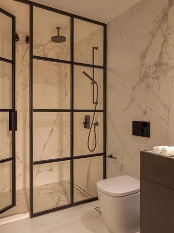 Modernes Badezimmer mit rahmenloser Glasdusche und Marmorfliesen.