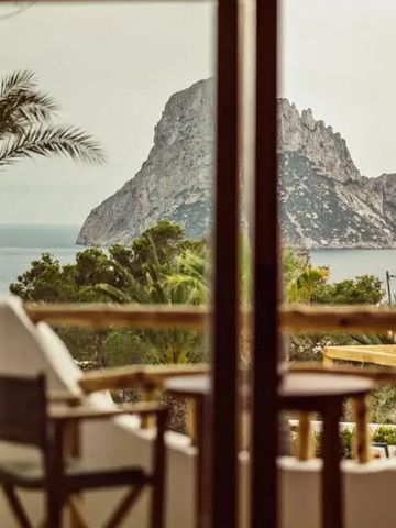 Panoramablick auf das Meer und die Felsen von Ibiza durch Glasfenster von einem Balkon aus