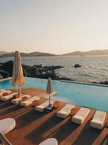 Infinity-Pool mit Blick aufs Meer bei Sonnenuntergang und stilvollen Liegen.