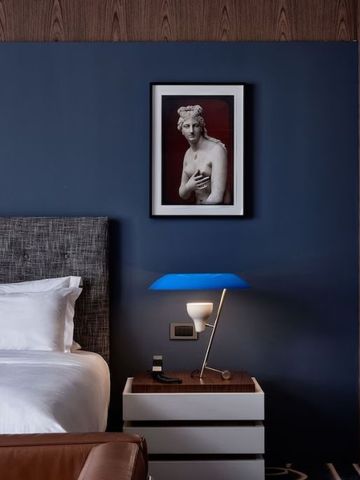 Elegantes Hotelzimmer mit Kunstwerk an der Wand und blauer Lampe.
